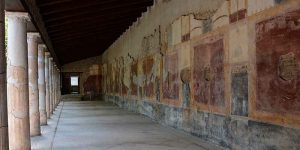Pórtico con columnas y paredes pintadas con grandes paneles rojos en un yacimiento romano.