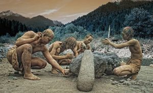 Recreación histórica que muestra a un grupo de homínidos prehistóricos trabajando en equipo para tallar o construir con piedras grandes en un entorno natural montañoso
