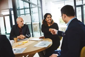 grupo de empresa en mesa redonda, estrechando manos de acuerdo