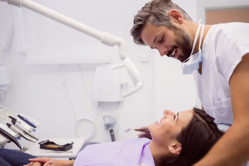 Dentista sonriente revisando a una paciente en una clínica dental.