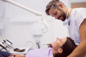 Dentista sonriente revisando a una paciente en una clínica dental.