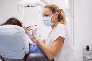 Dentista con mascarilla atendiendo a una paciente en una clínica dental.
