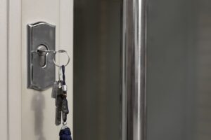 Primer plano de una llave insertada en la cerradura de una puerta, con llavero metálico colgando y fondo desenfocado en un entorno interior.