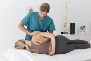 Fisioterapeuta realizando una movilización de espalda a una paciente en una camilla.