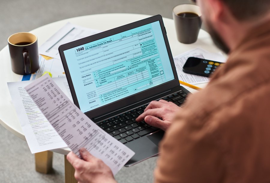 Hombre revisando documentos fiscales y facturas con un ordenador en su despacho